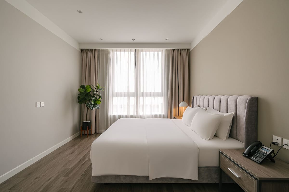 Ein modernes Hotelzimmer mit einem großen Bett, einem Nachttisch mit Lampe und einem Telefon.