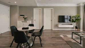 Ein modernes Wohnzimmer mit Essbereich, einem wandmontierten Flachbildfernseher und einem Topf mit Pflanze.