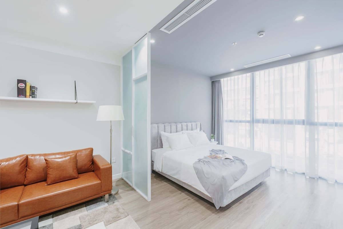 Ein modernes Hotelzimmer mit einem Bett, einem Schlafsofa, einem Nachttisch und einem großen Fenster.