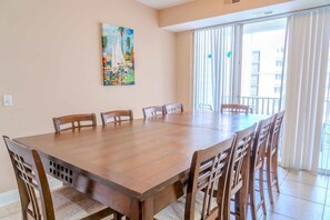 Un comedor con una gran mesa de madera y sillas, un cuadro en la pared y vistas a través de puertas de cristal.