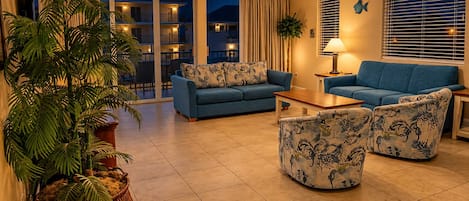 A living room with a sofa, armchairs, a coffee table, and a large potted plant.