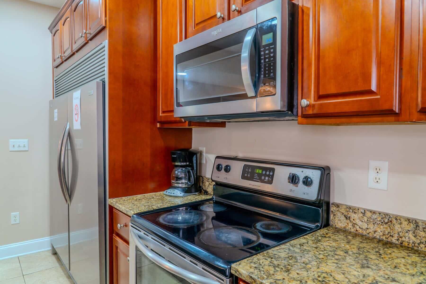 A kitchen with wooden cabinets, a stainless steel microwave, a gas stove, and a coffee maker.