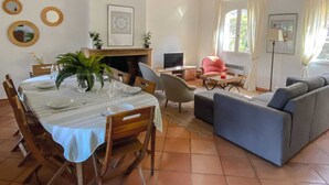 A dining area with a table set for four, a sofa, and a television in a living room.