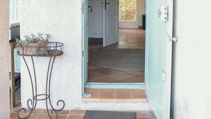 A doorway leading into a room with a tiled floor and a small table with plants.