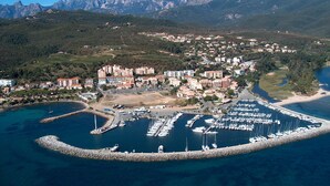 Vue aérienne d’une ville côtière avec un port de plaisance, des immeubles résidentiels et, au loin, un paysage montagneux.