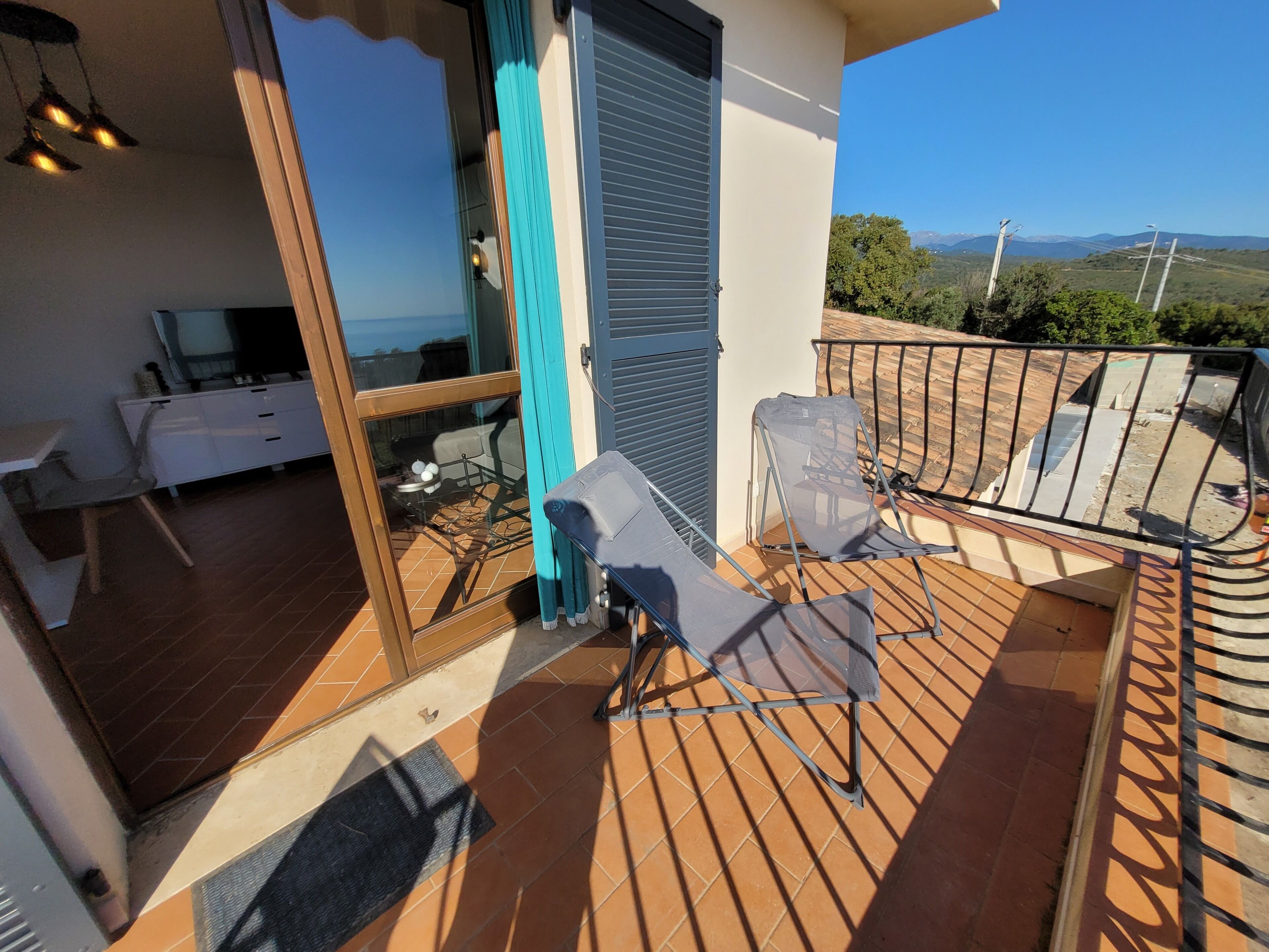 Een balkon met twee stoelen, een tafel en een bank.
