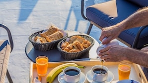 A breakfast tray with bread, fruits, coffee, and juice on a terrace with outdoor seating. - Acropolis Vision (Athens)