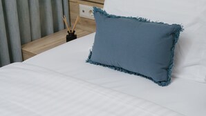 A neatly made bed with a blue pillow and a magazine on it. - Acropolis Vision (Athens)