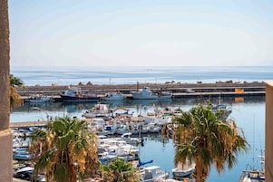Un puerto deportivo con barcos amarrados, palmeras y una vista despejada del mar.