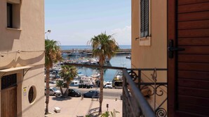 Un balcón con vistas a un puerto deportivo, palmeras y coches estacionados.