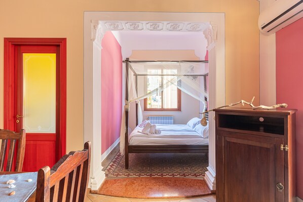 Un dormitorio con una cama con dosel, un armario de madera y una puerta roja.