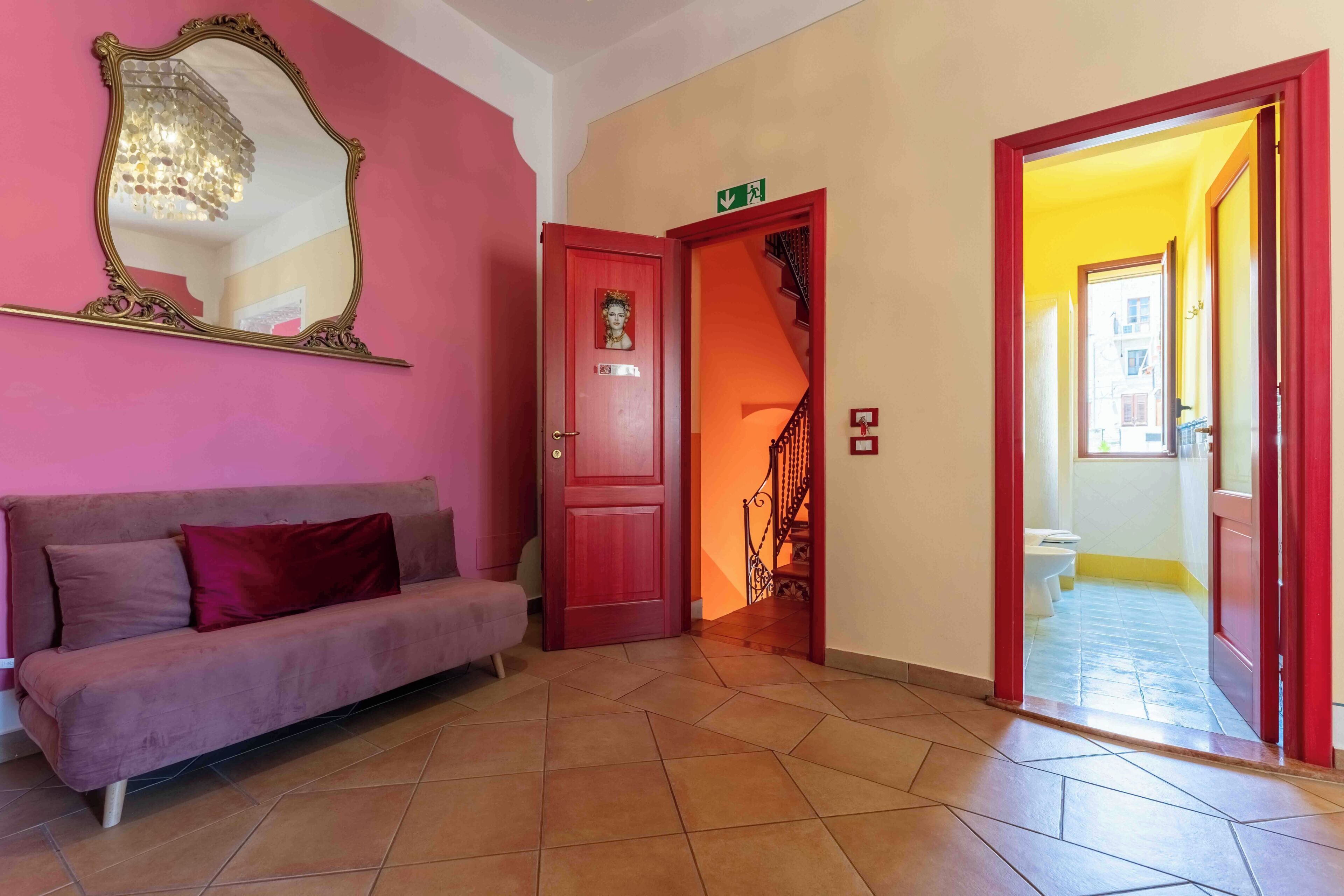 A room with a sofa, a mirror, a door, and a staircase.
