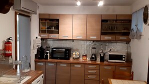 A compact kitchen with wooden cabinets, a microwave, a coffee maker, and a sink. - 50 m2 apartment in villa (GRASSE)