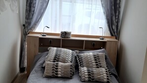 A bedroom with a bed, a window with curtains, a desk, and a small table. - 50 m2 apartment in villa (GRASSE)