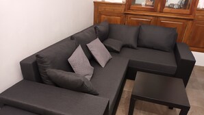 A sectional sofa with a matching ottoman and a small table in a living room with wooden cabinets in the background. - 50 m2 apartment in villa (GRASSE)