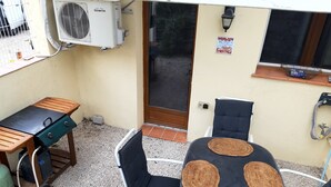 An outdoor patio with a grill, a table with woven placemats, and a chair. - 50 m2 apartment in villa (GRASSE)