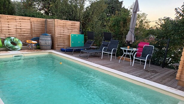 A swimming pool with a wooden deck, lounge chairs, and a table. - 50 m2 apartment in villa (GRASSE)