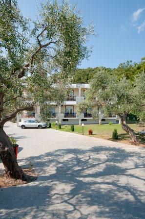 A building with balconies, a paved driveway, and a parked car.