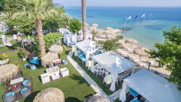 A resort with outdoor seating, palm trees, and a view of the sea.