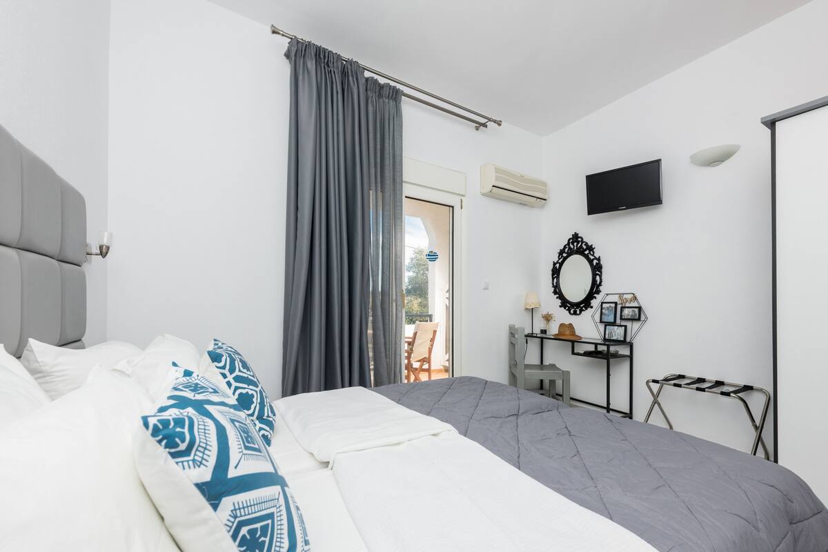 A bedroom with a bed, a desk, a chair, and a TV.