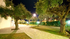 A nighttime outdoor pathway lined with trees and illuminated by streetlights.