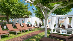 A sunlit outdoor lounge area with wicker lounge chairs and a wooden pathway.