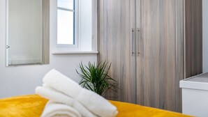 A bedroom with a bed, a window, a plant, and a wardrobe. - The Holt (Lincoln)
