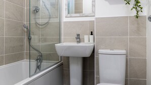 A modern bathroom with a glass-enclosed shower, a pedestal sink, and a toilet. - The Holt (Lincoln)
