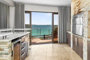 A modern kitchen with a large sliding glass door leading to a balcony with a sea view. - Tenos On Calypso 16 (Langebaan)