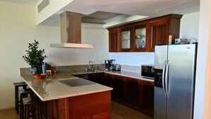 Une cuisine moderne dotée d’un îlot central, d’appareils électroménagers en acier inoxydable, de meubles de rangement en bois et d’un four à micro-ondes encastré.