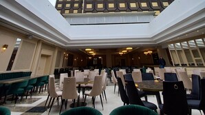 Un espacio interior amplio con techo alto y tragaluces, con un edificio moderno de fachada geométrica al fondo.