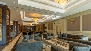 Un vestíbulo amplio con modernos arreglos de asientos, incluyendo sofás y sillones, y una araña.