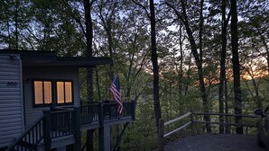 A cabin with a deck, an American flag, and a forested backdrop. - Mountain Cabin in the woods-Tranquil Setting-2 bed 2 bath-Private-Deck-Views (Brasstown)