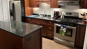 A kitchen with wooden cabinets, a stainless steel refrigerator, a gas stove, and a built-in oven. - Mountain Cabin in the woods-Tranquil Setting-2 bed 2 bath-Private-Deck-Views (Brasstown)