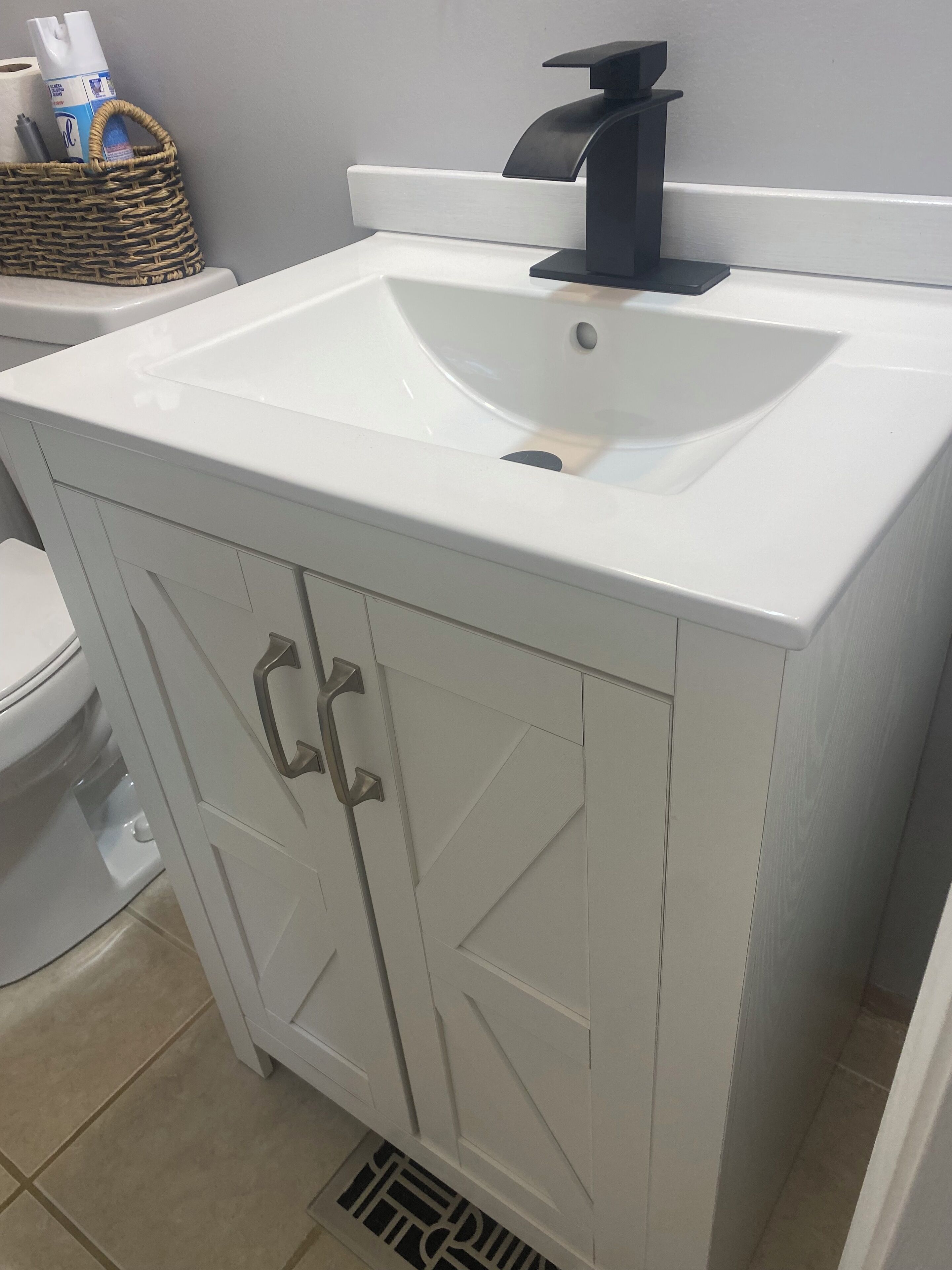 Une salle de bain avec un lavabo blanc, des toilettes et un meuble avec des tiroirs.
