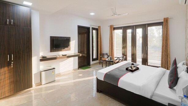 Una habitación de hotel moderna con cama, televisión, escritorio y una pequeña kitchenette.