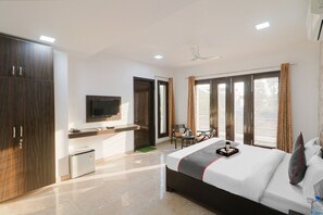 A modern hotel room with a bed, a TV, a desk, and a small kitchenette. - Dreamz Hospitality 2 (Gurugram)