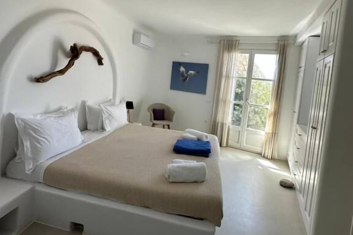 Een moderne slaapkamer met een bed, een stoel, een bureau en een raam.