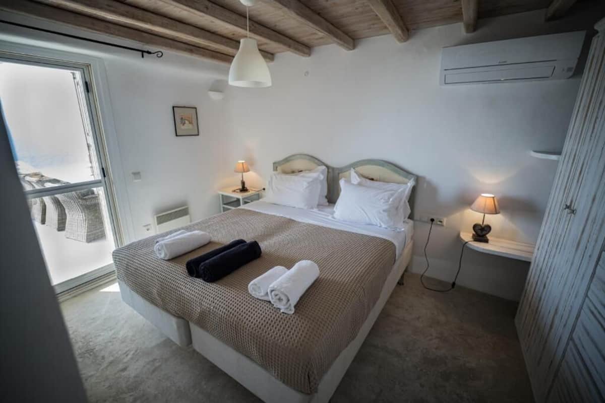 Een slaapkamer met een groot bed, twee nachtkastjes, een raam en een airconditioning.