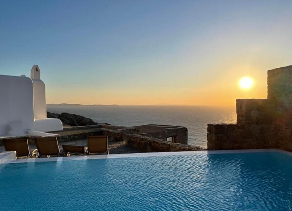 Una piscina infinita con vistas al mar al atardecer.