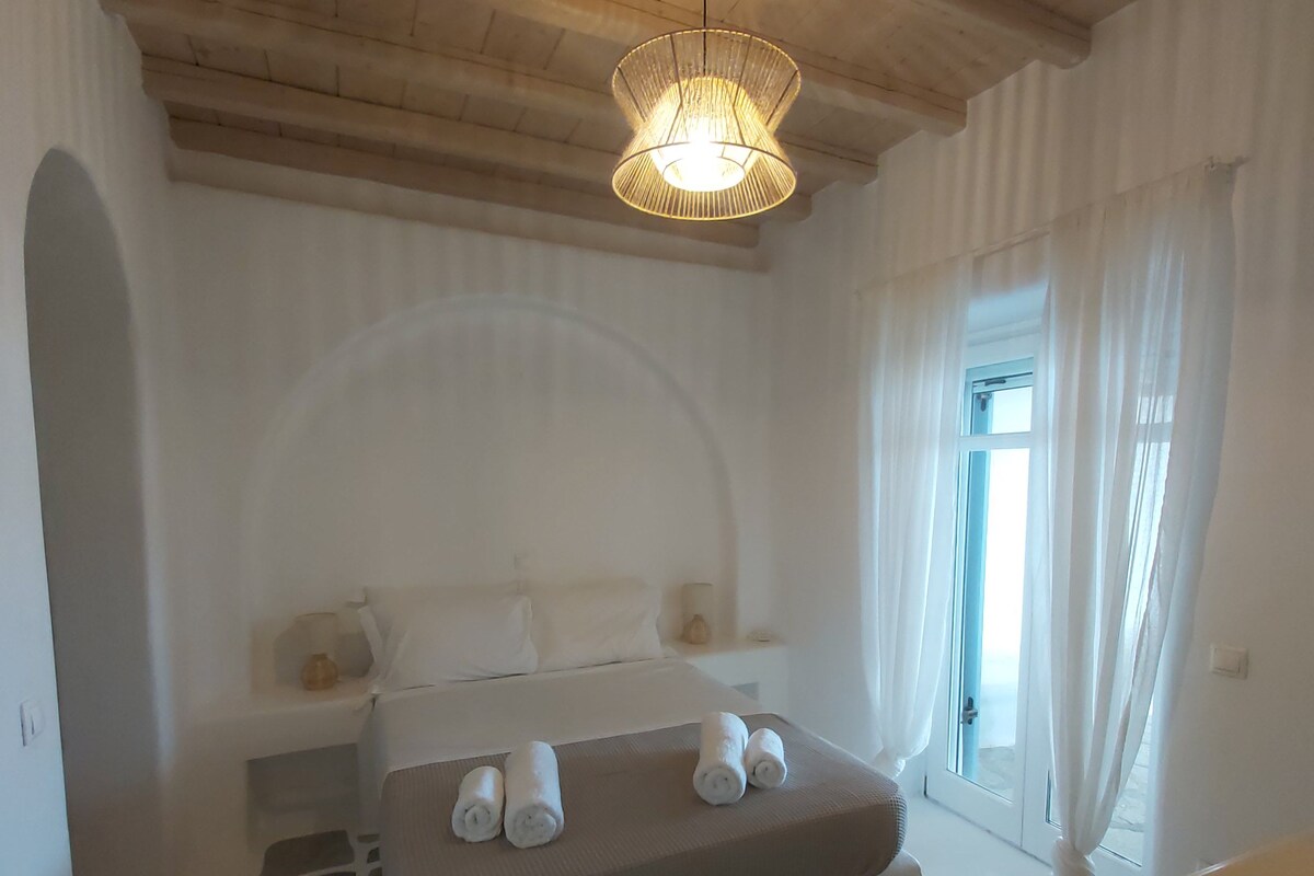 Un dormitorio con cama, piso de diseño de piedra, techo de madera y lámpara colgante.