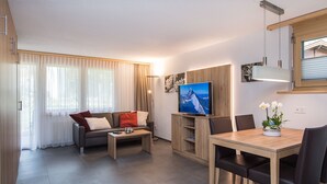 Un salon moderne comprenant un canapé, une table basse, un téléviseur et un coin repas.