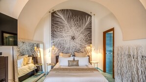 A spacious bedroom with a large bed, a TV, and a decorative wall.
