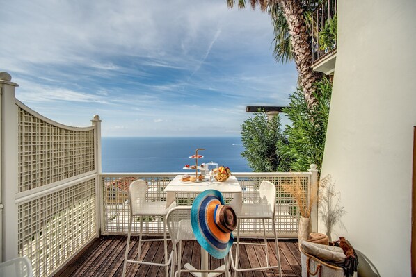 A terrace with a table set for a meal, chairs, and a view of the sea. - Honeymooners nest in Amalfi coast  (Marciano)