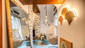 A cozy room with a large mirror, wicker chairs, a round seating area, and decorative wall sconces.