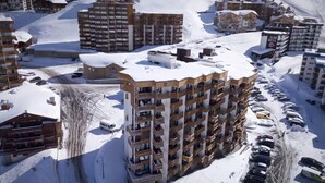 A high-rise hotel with multiple balconies, surrounded by snow-covered roads and other buildings. - 100m from ski slopes, 1st floor, terrace, balcony, tv, 90m², Val Thorens (Val Thorens)