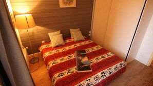A bedroom with a bed covered in a patterned blanket, a bedside lamp, and a framed picture on the wall. - 100m from ski slopes, 1st floor, terrace, balcony, tv, 90m², Val Thorens (Val Thorens)