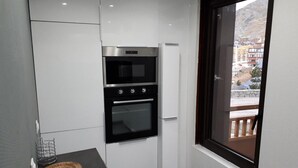 A compact kitchen with a built-in oven and a window with a view of buildings and a balcony. - 100m from ski slopes, 1st floor, terrace, balcony, tv, 90m², Val Thorens (Val Thorens)