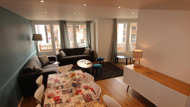 A modern living room with a dining table, sofa, and a small kitchen area. - 100m from ski slopes, 1st floor, terrace, balcony, tv, 90m², Val Thorens (Val Thorens)