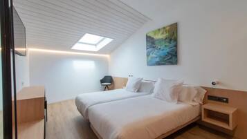 A modern bedroom with a skylight, a bed, a nightstand, and a chair.